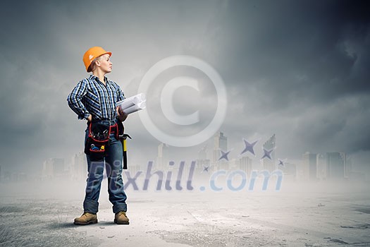 Young woman in hardhat with construction project in hands Young woman in hardhat with construction project in hands