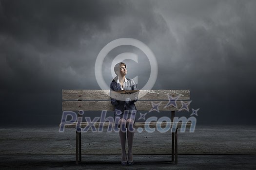 Young smiling businesswoman sitting on bench with book in hands Young smiling businesswoman sitting on bench with book in hands