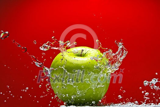 Green apple with water splash on red background Green apple with water splash on red background