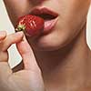 Young woman biting strawberry isolated on white