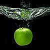 green apple dropped into water with splash isolated on black