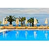 Idyllic swimming pool at tropical resort with palm trees in Greece