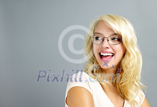 Happy young woman wearing eyeglasses looking to the side on grey background Happy young woman wearing eyeglasses looking to the side on grey background