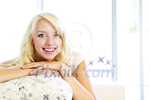 Portrait of smiling blonde woman relaxing on couch in living room at home Portrait of smiling blonde woman relaxing on couch in living room at home