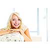 Portrait of smiling blonde woman relaxing on couch in living room at home