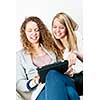 Two young smiling women using tablet computer at home