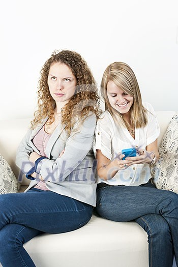 Young woman ignoring her friend checking smart phone breaching cellphone etiquette Young woman ignoring her friend checking smart phone breaching cellphone etiquette