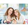 Two happy women in cafe celebrating with glasses of white wine