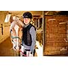 Portrait of teenage girl with horse in stable