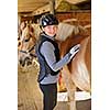 Portrait of teenage girl with horse in stable