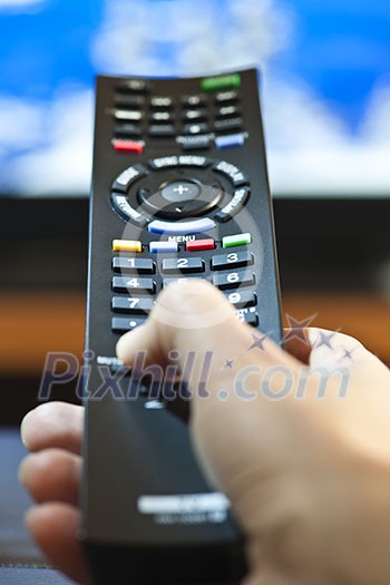 Hand holding television remote control pressing buttons Hand holding television remote control pressing buttons