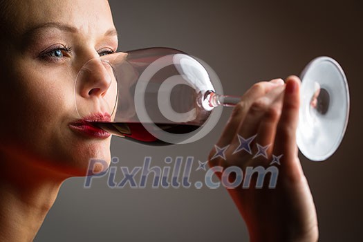 Elegant young woman in a red dress, having a glass of red wine Elegant young woman in a red dress, having a glass of red wine