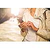 Young woman messaging/using app on her smart-phone in a city street context (shallow DOF; color toned image)