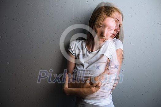 Young woman suffering from a severe depression/anxiety (color toned image; double exposure technique is used to convey the mood of unease, progression of the anxiety/depression) Young woman suffering from a severe depression/anxiety (color toned image; double exposure technique is used to convey the mood of unease, progression of the anxiety/depression)