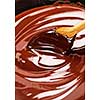 Wooden spoon stirring soft melted rich chocolate