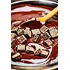 Wooden spoon stirring melting rich chocolate chunks