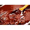 Wooden spoon stirring melting rich chocolate chunks