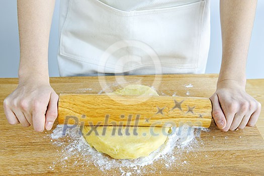 Spreading out cookie dough with wooden rolling pin Spreading out cookie dough with wooden rolling pin