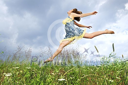 Young teenage girl jumping in summer meadow amid wildflowers Young teenage girl jumping in summer meadow amid wildflowers