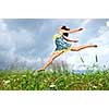 Young teenage girl jumping in summer meadow amid wildflowers