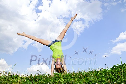 Young teenage girl doing cartwheel in a summer meadow Young teenage girl doing cartwheel in a summer meadow