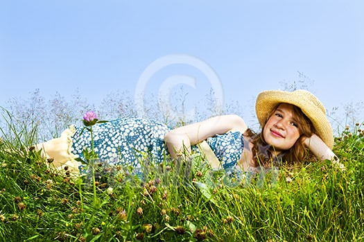 Young teenage girl laying on summer meadow in straw hat Young teenage girl laying on summer meadow in straw hat