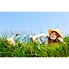 Young teenage girl laying on summer meadow in straw hat