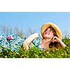 Young teenage girl laying on summer meadow in straw hat looking up