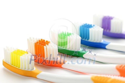 Close up of multicolored toothbrushes on white background Close up of multicolored toothbrushes on white background