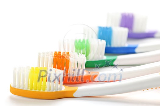 Close up of multicolored toothbrushes on white background Close up of multicolored toothbrushes on white background