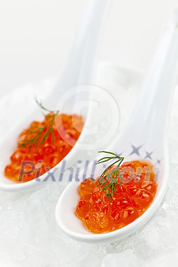 Closeup of caviar with dill garnish in two white spoons on ice Closeup of caviar with dill garnish in two white spoons on ice
