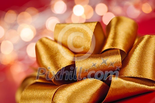 Golden ribbon gift bow closeup with festive lights Golden ribbon gift bow closeup with festive lights