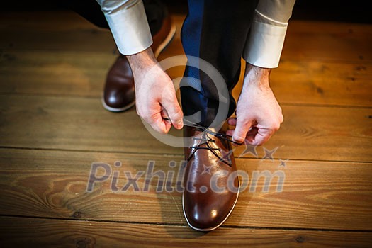 Handsome groom on his wedding day - tying a shoe lace Handsome groom on his wedding day - tying a shoe lace