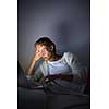 Very tired young woman, burning the midnigh oil - working late at night on her laptop computer, at home, sitting on sofa, rubbing her tired eyes, trying to stay focused