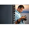 Handsome young photographer using his modern DSLR outdoors, against lovely sky backdrop (color toned image;shallow DOF)