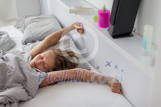 Pretty, young woman stretching in bed after waking up