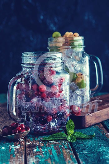 Fresh berries with ice in mason jar on dark background. Detox diet. Retro toned instagram style. Fresh berries with ice in mason jar on dark background. Detox diet. Retro toned instagram style.
