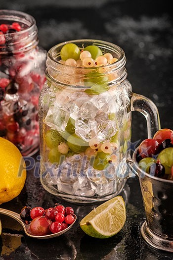 Fresh berries with ice in mason jar on dark background. Detox diet. Fresh berries with ice in mason jar on dark background. Detox diet.