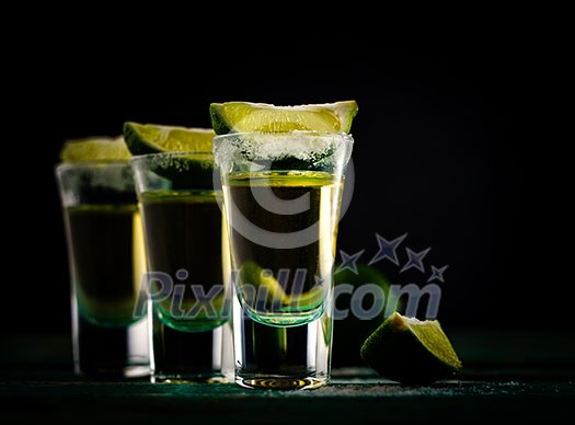 Mexican Gold Tequila with lime and salt on dark background, selective focus. Mexican Gold Tequila with lime and salt on dark background, selective focus.