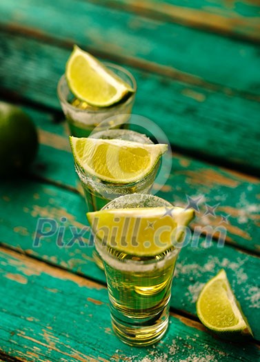 Mexican Gold Tequila with lime and salt on wooden table, selective focus. Mexican Gold Tequila with lime and salt on wooden table, selective focus.