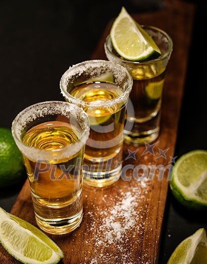 Mexican Gold Tequila with lime and salt on wooden table, selective focus. Mexican Gold Tequila with lime and salt on wooden table, selective focus.