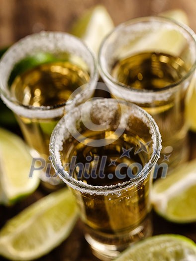 Mexican Gold Tequila with lime and salt on wooden table, selective focus. Top view. Shallow depth of field. Mexican Gold Tequila with lime and salt on wooden table, selective focus. Top view. Shallow depth of field.