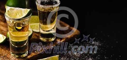 Two Gold tequila shots with lime, copy space on right side. Gold Mexican tequila. Alcohol drink. Two Gold tequila shots with lime, copy space on right side. Gold Mexican tequila. Alcohol drink.