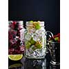 Fresh berries with ice in mason jar on dark background. Detox diet.