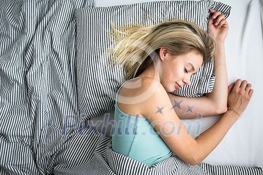 Beautiful young woman sleeping in bed (color toned image; shallow DOF)