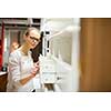 Pretty, young woman choosing the right furniture for her apartment in a modern home furnishings store (color toned image; shallow DOF)