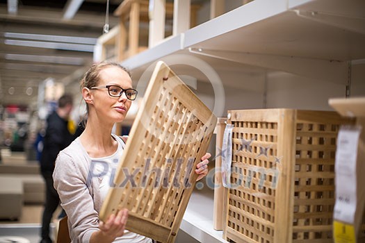 Pretty, young woman choosing the right furniture for her apartment in a modern home furnishings store (color toned image; shallow DOF) Pretty, young woman choosing the right furniture for her apartment in a modern home furnishings store (color toned image; shallow DOF)