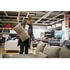 Pretty, young woman choosing the right furniture for her apartment in a modern home furnishings store (color toned image; shallow DOF)