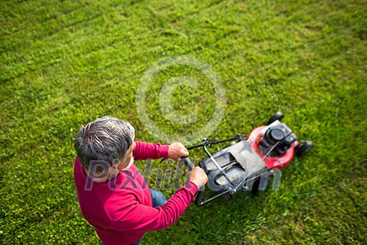 Senior man mowing his garden - shot from above - interesting angle view Senior man mowing his garden - shot from above - interesting angle view
