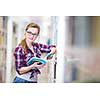 Pretty, female college student in a library, looking for a book (shallow DOF; color toned image)